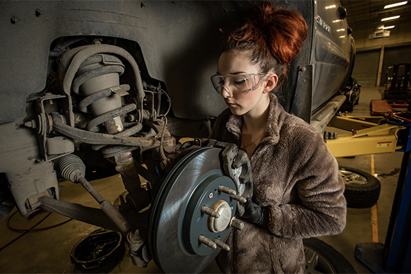 Female student works in auto shop